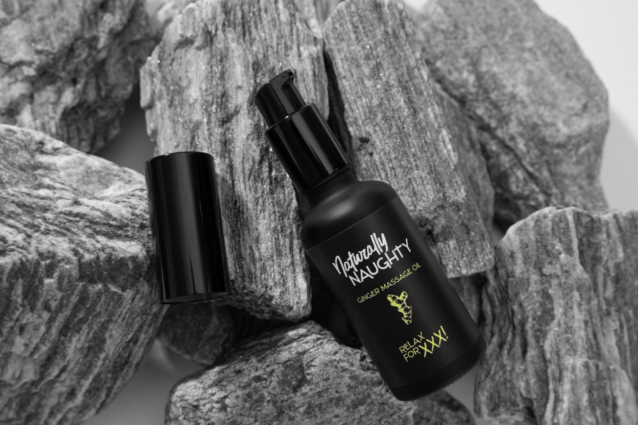 Produktbild: Die schwarze Pump-Glasflasche des Ingwer Massageöls steht auf einem Felsvorsprung einer Felswand. Der Deckel ist ab.